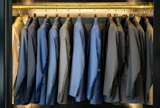 Ajuste de trajes, varios sacos de diferentes colores colgados en un perchero metálico