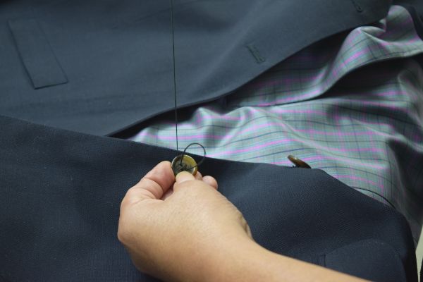Compostura de ropa; sastre realizando la colocación de un botón faltante