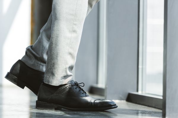 Pantalones de hombre elegante de negocios de pie con zapatos negros y pantalones de vestir de moda.
