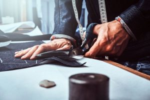 Reparación de ropa; hombre cortando con tijeras especiales, tela negra