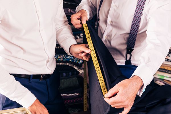 Reparación de ropa; sastre midiendo con una cinta métrica un traje