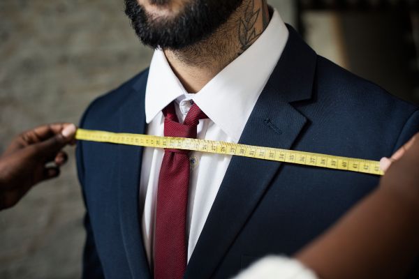 Traje a la medida; midiendo el traje de color azul al cliente