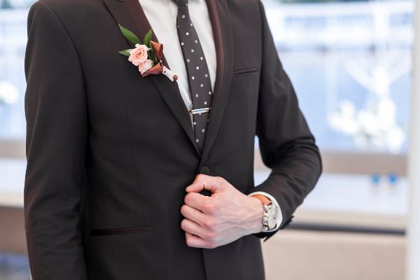 Trajes de novio para boda; traje de color negro con una flor rosa